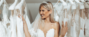 Bride wearing a strapless lace wedding dress around all the wedding dresses hanging up. 