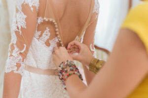 Maid of Honor buttoning the brides wedding dress. 