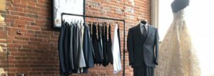 Tuxedos and vests hanging on a rack.