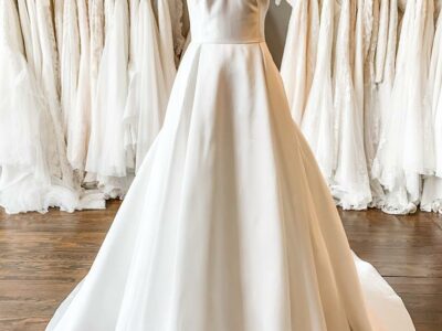 white off-shoulder wedding dress displayed on mannequin