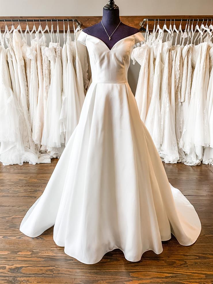 white off-shoulder wedding dress displayed on mannequin