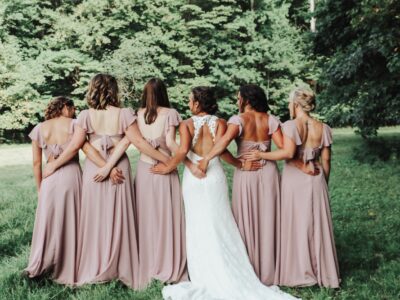 bride and her five bridesmaid walking into lush forest area